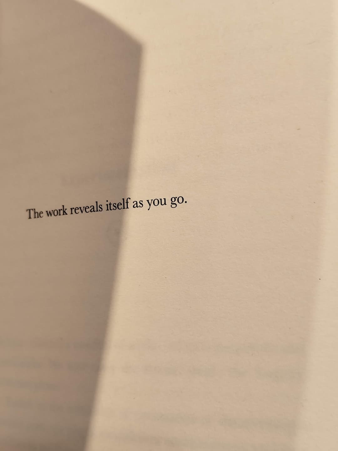 A page in a physical book with a line of text saying "The work reveals itself as you go."