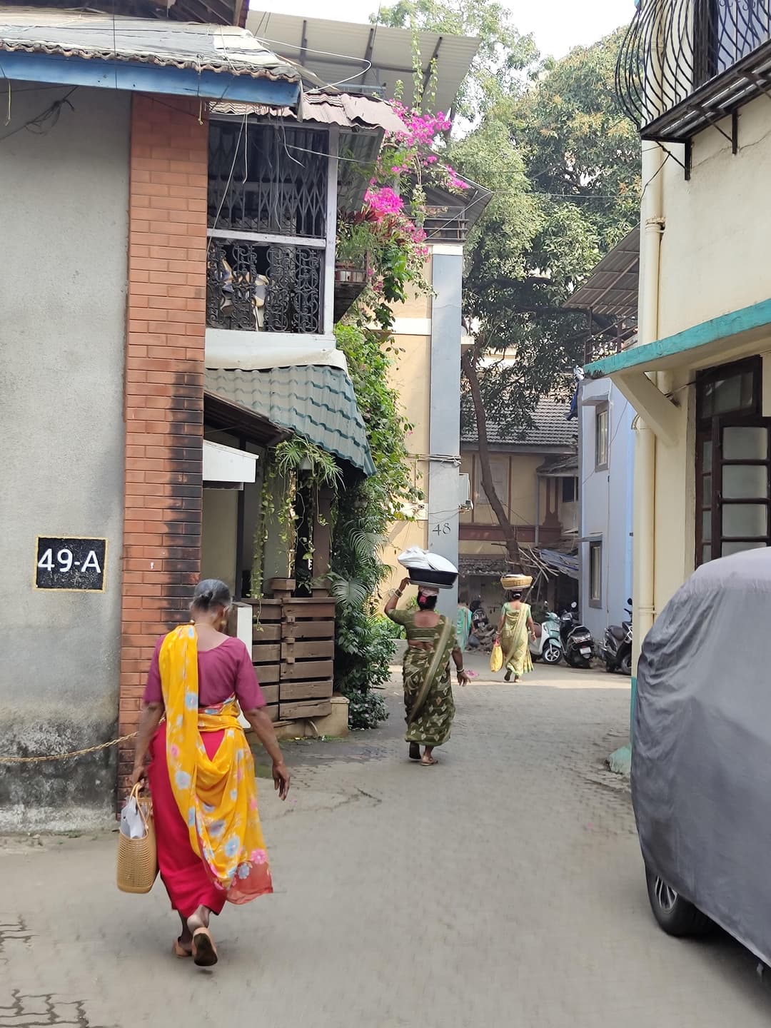Three women dressed in saris walking down an alley in Bandra West, Mumbai