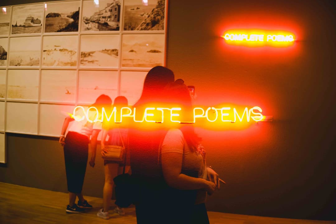 Photograph of two museum visitors looking at artwork hanging on wall