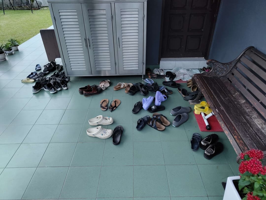 A group of shoes gathered on the floor at the main entrance door of a house